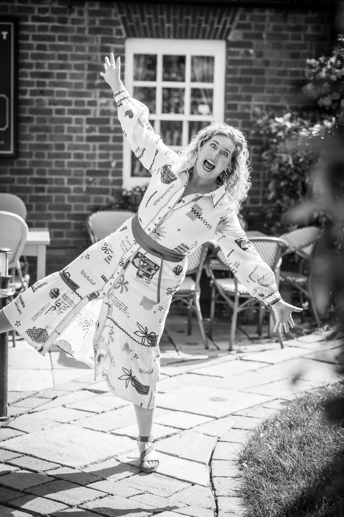 Tanya dancing in a garden, arms wide, in black and white