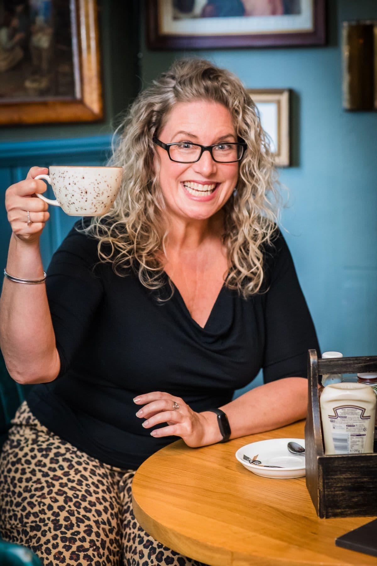 Tanya with a coffee and glasses, mid smile